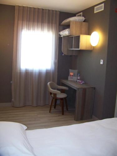 a bedroom with a bed and a desk and a window at ibis Styles Vierzon in Vierzon