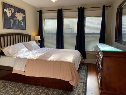 um quarto com uma cama, uma cómoda e janelas em Historic Downtown Riverview Flat, No. 1 em Astoria