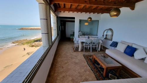 balcón con sofá y mesa en la playa en Chambre bord de mer, en Asilah