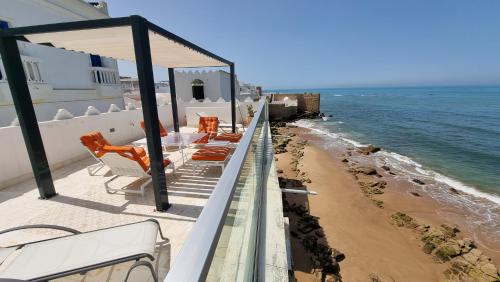 a balcony with chairs and a table and the ocean at Chambre bord de mer in Asilah