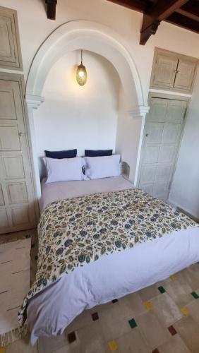 Un dormitorio con una cama grande con un arco encima. en Chambre bord de mer, en Asilah