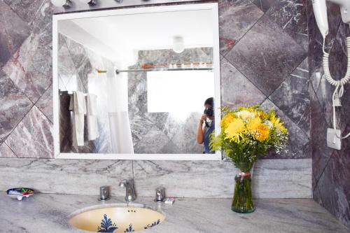 a bathroom with a sink and a vase of flowers at Hotel Delfin in Playa del Carmen