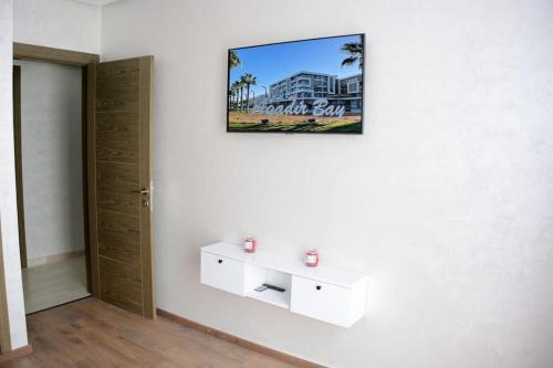 AGADIR BAY Appartement de haut standing 140m2 في أغادير: غرفة بجدار أبيض مع صورة على الحائط