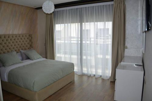 AGADIR BAY Appartement de haut standing 140m2 في أغادير: غرفة نوم بسرير ونافذة كبيرة