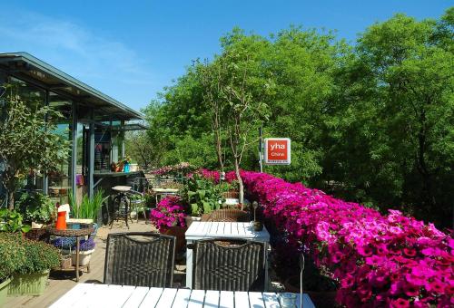 a garden with purple flowers and a table and chairs at Peking Youth Hostel in Beijing