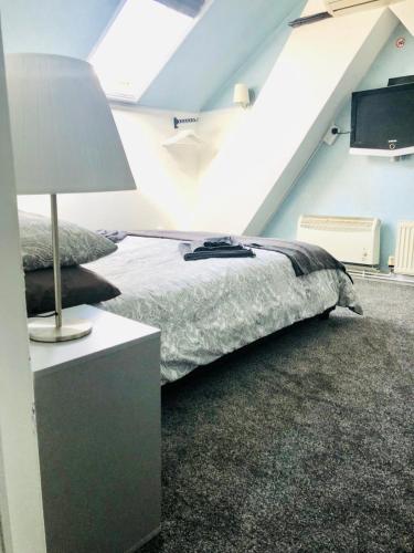 een slaapkamer met een bed en een tafel met een lamp bij AC Hideout in Rochford
