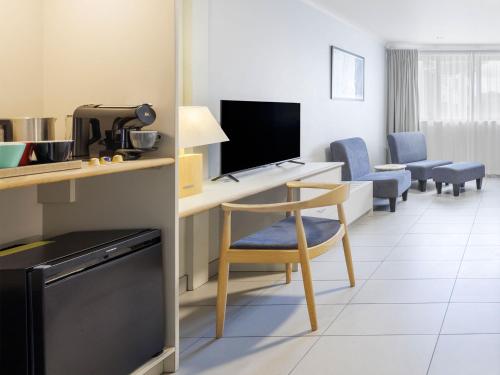 a room with a desk with a chair and a television at JetPark Hotel Rotorua in Rotorua