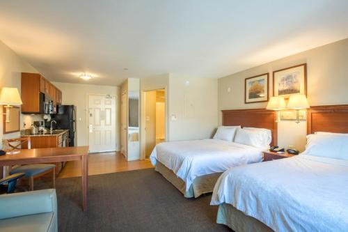Habitación de hotel con 2 camas, escritorio y cocina en Western Slope Suites Parachute, en Parachute