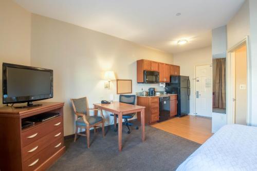 a hotel room with a table and a kitchen with a television at Western Slope Suites Parachute in Parachute