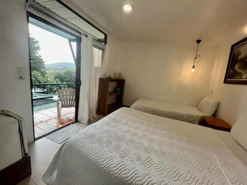 1 dormitorio con 2 camas y vistas a un balcón en Freddy`s Place B&B, en Monteverde