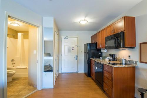 a kitchen with wooden cabinets and a black refrigerator at Western Slope Suites Parachute in Parachute