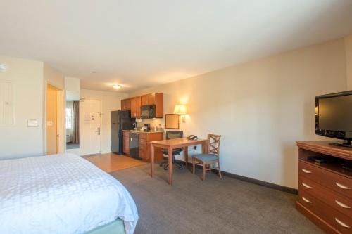 a hotel room with a bed and a desk and a television at Western Slope Suites Parachute in Parachute