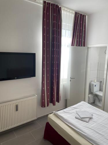 a bedroom with a bed and a flat screen tv at Pension-Wob 2 in Wolfsburg