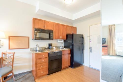 a kitchen with wooden cabinets and a black refrigerator at Western Slope Suites Parachute in Parachute