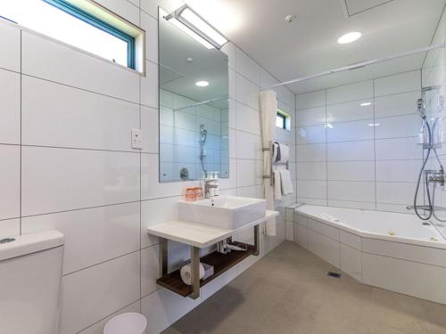 JetPark Hamilton Airport New Zealand في هاميلتون: حمام أبيض مع حوض وحوض استحمام