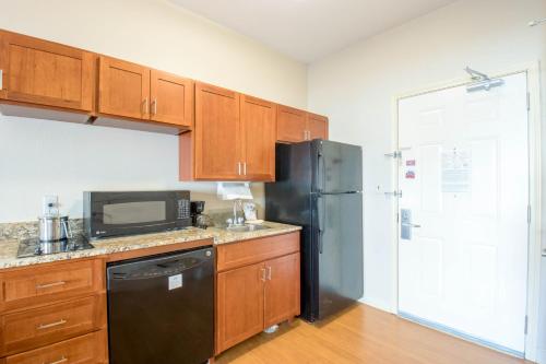 a kitchen with wooden cabinets and a black refrigerator at Western Slope Suites Parachute in Parachute