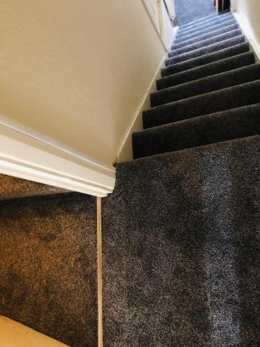 a staircase with black carpeted floors and a stair case at AC Hideout in Rochford
