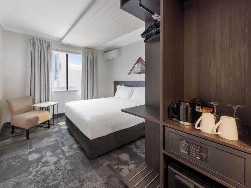 a hotel room with a bed and a chair at JetPark Auckland Airport Hotel in Auckland