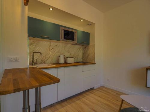 une cuisine avec des armoires blanches, un évier et un micro-ondes dans l'établissement Studio Meublé à Bagneux, avec climatisation et parking payants, à Bagneux