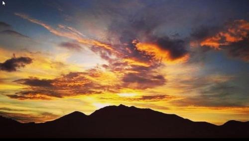 a sunset over the top of a mountain at Alto Paraíso Glamping Carmen de Viboral in Rionegro