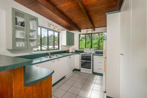 a kitchen with white cabinets and green counter tops at The Cooks Oasis in Rarotonga