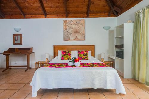a bedroom with a white bed with flowers on it at The Cooks Oasis in Rarotonga