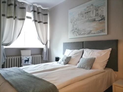 een slaapkamer met een bed met witte lakens en een raam bij Metro Wilson Apartment in Warschau