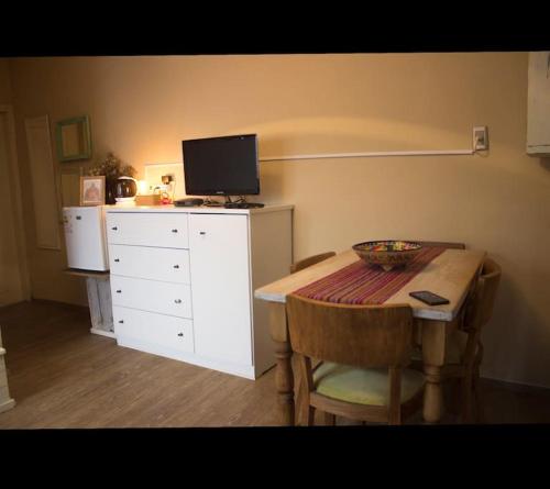 a room with a table and a white dresser with a television at Apartamento independiente en alquiler En casa de familia in Montevideo