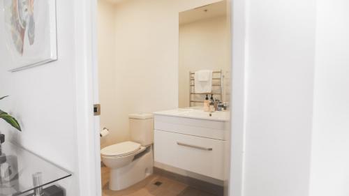 a white bathroom with a toilet and a sink at Pinnacle Apartment in Auckland