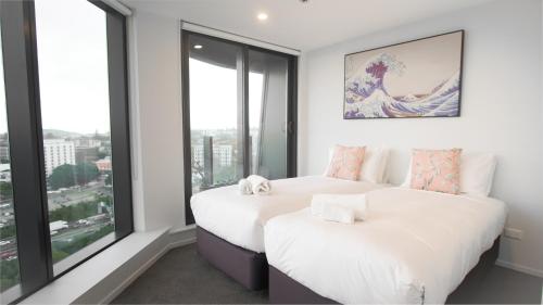 two beds in a room with large windows at Pinnacle Apartment in Auckland