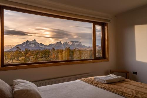 a bedroom with a large window with a mountain view at Pampa Lodge, Quincho & Caballos in Torres del Paine