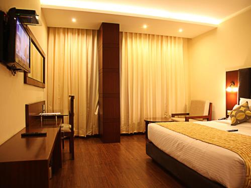a hotel room with a bed and a desk at Hotel Cama in Chandīgarh