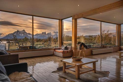 sala de estar con ventanas grandes y mesa en Pampa Lodge, Quincho & Caballos, en Torres del Paine