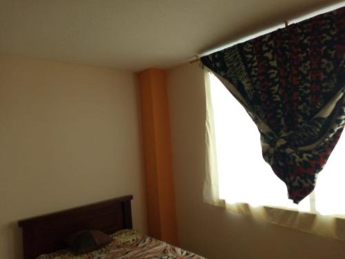 a bedroom with a bed and a window with a curtain at Sun Habitacion Privada in Riobamba
