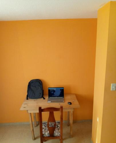 a table with a laptop and a backpack on it at Sun Habitacion Privada in Riobamba