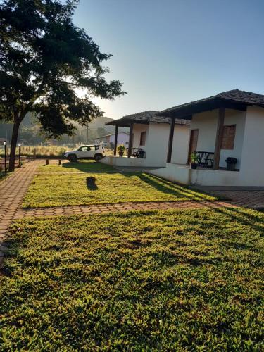 uma casa com um carro estacionado ao lado de um campo de relva em Chalés por do sol em Pirenópolis