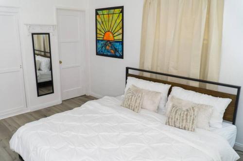 a bedroom with a white bed with pillows and a window at Artful Retreat - King Bed, Work Desk, WIFI, Unique Murals, Perfect for Business Travelers, Downtown & Near Universal Studios in Burbank