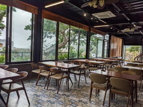 a restaurant with tables and chairs and large windows at Eden Hotel Cát Bà in Cat Ba