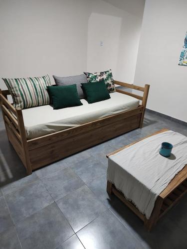 a wooden couch and a bed in a room at Duplex Del Valle in San Fernando del Valle de Catamarca