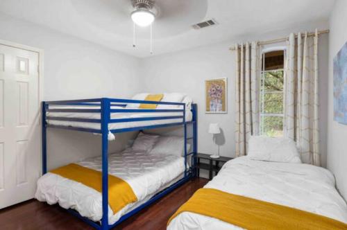 a bedroom with two bunk beds next to a window at Flamingo Pool Oasis with Covered Patio, BBQ, 4 BR in Katy