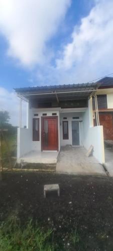 uma pequena casa branca com uma porta vermelha em Alvaiz home em Gunungsan