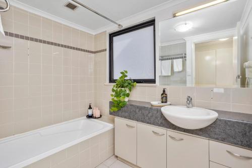 een badkamer met een wit bad, een wastafel en een spiegel bij Executive 2br Suite On Mounts Bay Road in Perth