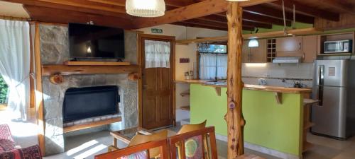 a kitchen with a fireplace and a television in a room at Paillahuen in Villa La Angostura