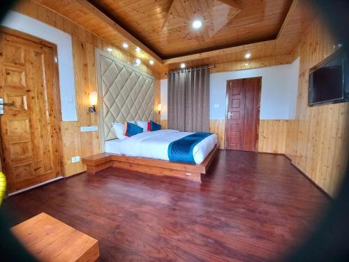 a bedroom with a bed in a room with wooden floors at Humble Holiday Home Kufri S H I M L A with Lawn and Amazing View in Kūfrī