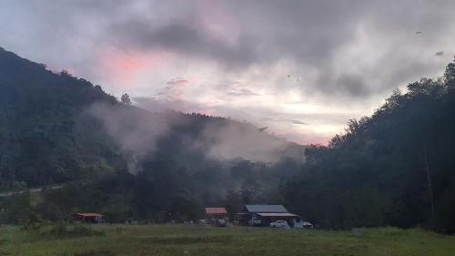 a rainbow in the sky over a field with a house at Kuriou Lodge & Campsite in Kiulu