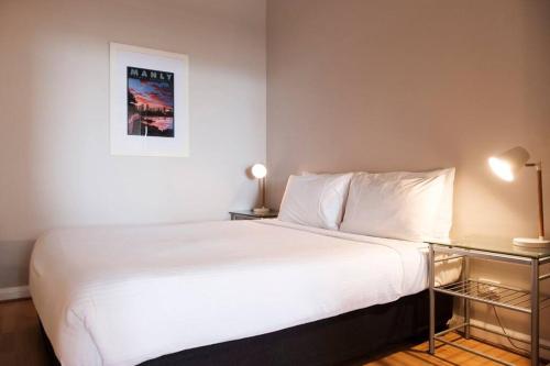 - une chambre avec un grand lit blanc et deux lampes dans l'établissement Ideal 1BR Suite near the Manly Beach with Pool, à Sydney
