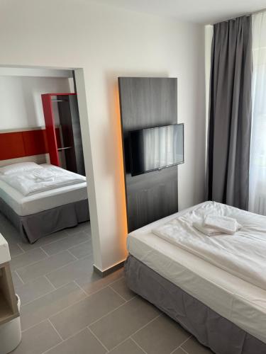 a bedroom with two beds and a flat screen tv at Pension Wob in Wolfsburg