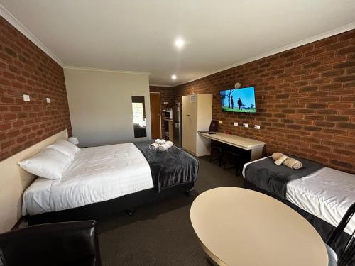 a hotel room with two beds and a brick wall at Balranald Colony Inn Motel in Balranald