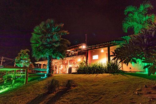 a house lit up at night with green lights at Rancho Recanto da Serra in Delfinópolis