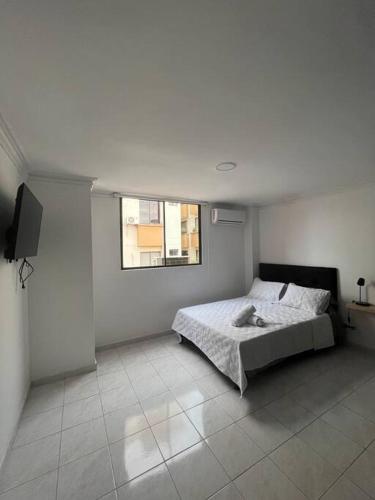 Habitación blanca con cama y ventana en Acogedor apto para 8 zona buenavista, en Barranquilla